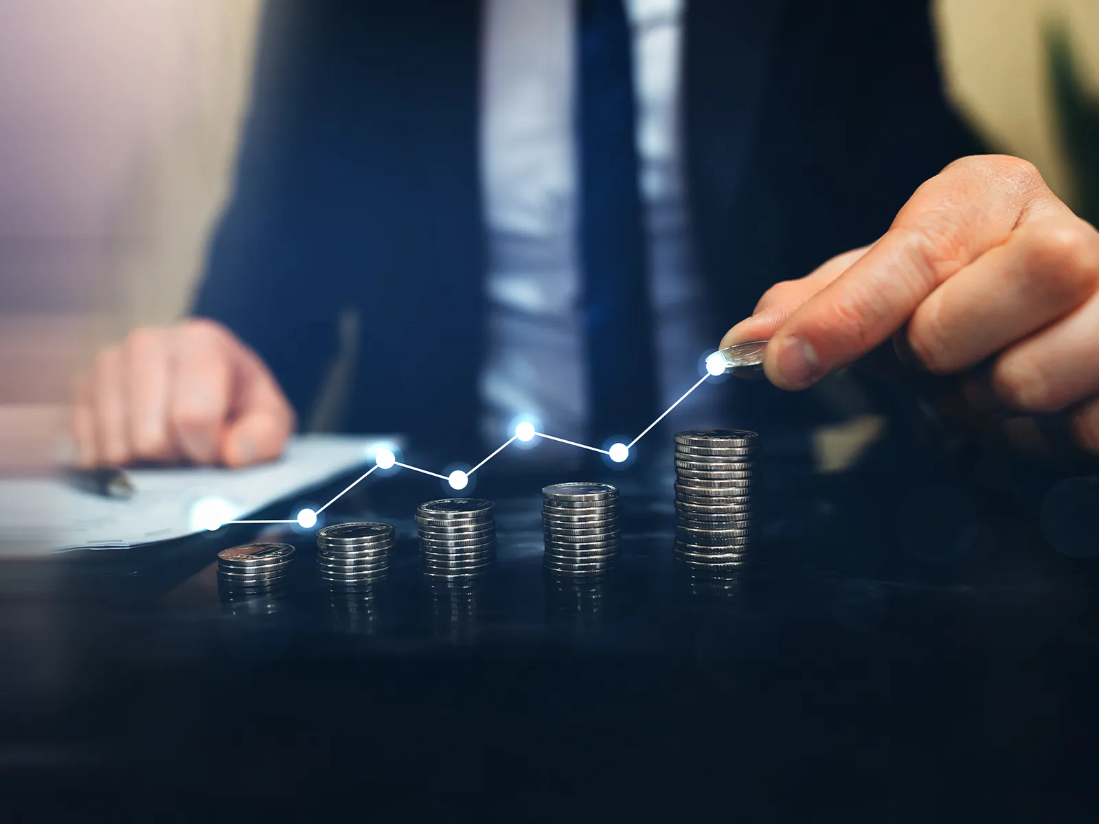 A man stacking coins with line graph overlay